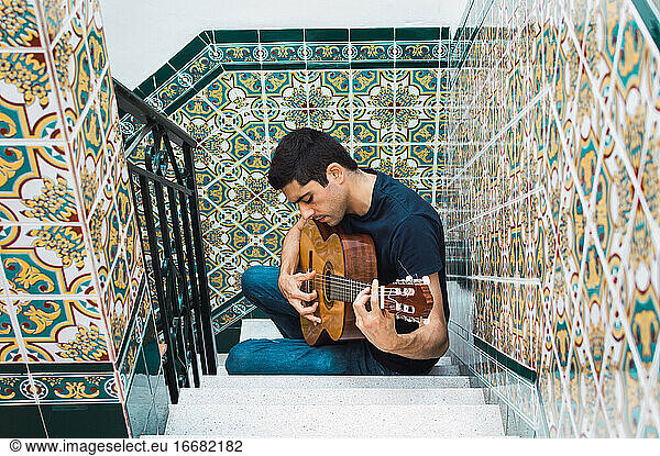 Young man playing spanish guitar in an andalusian courtyard.