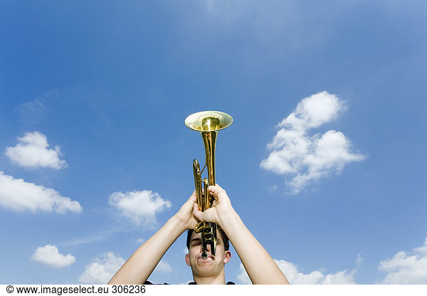 Young man playing trumpet  low angle view