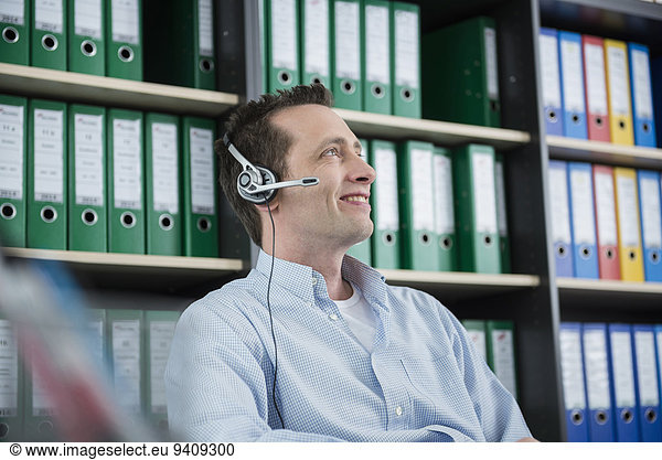 Young man portrait sitting office headset smiling