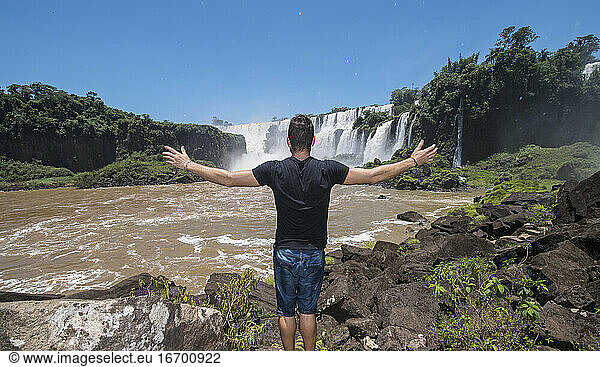 young man posing in front of the Iguacu waterfalls in Argentina