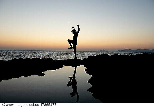 Young man practicing yoga at Sunset in Can Marroig in Formentera.