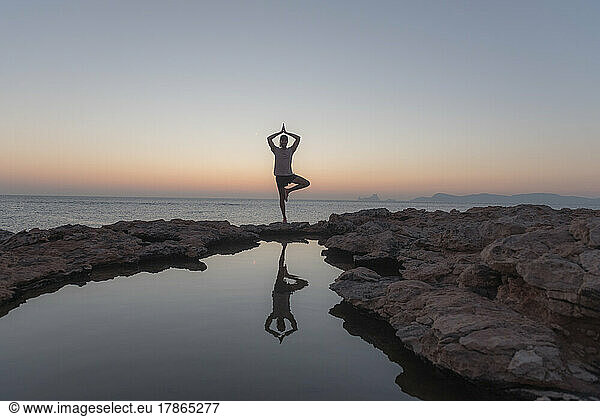 Young man practicing yoga at Sunset in Can Marroig in Formentera