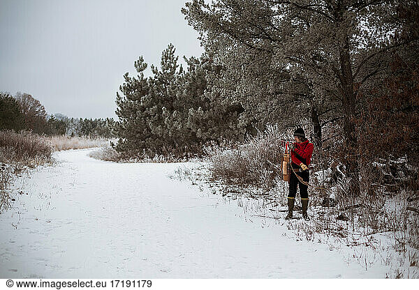 Young man pulling arrow out of vintage quiver in winter woods