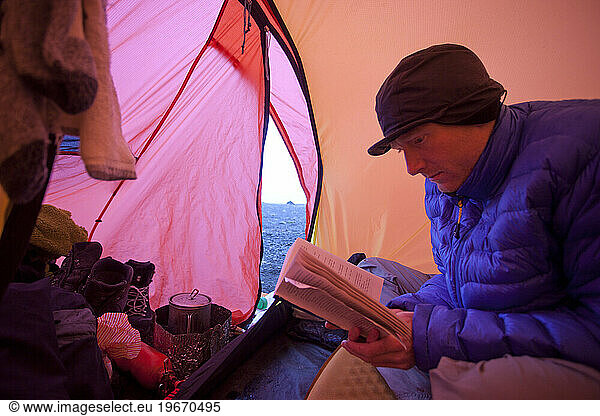 Young man reading book in a tent in Iceland