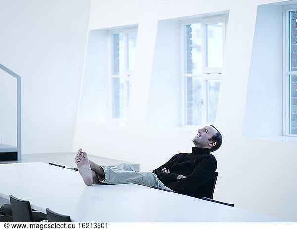 Young man relaxing with feet up on table  smiling