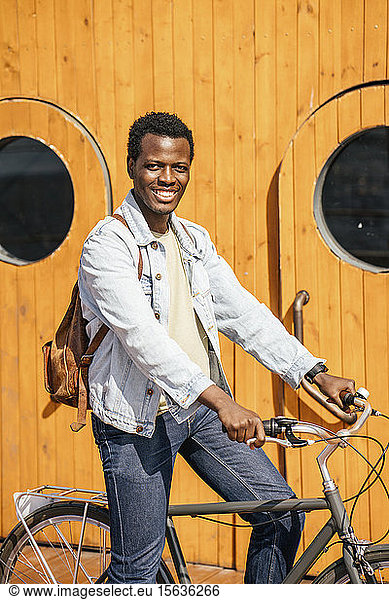 Young man riding bicycle in front of wooden doors