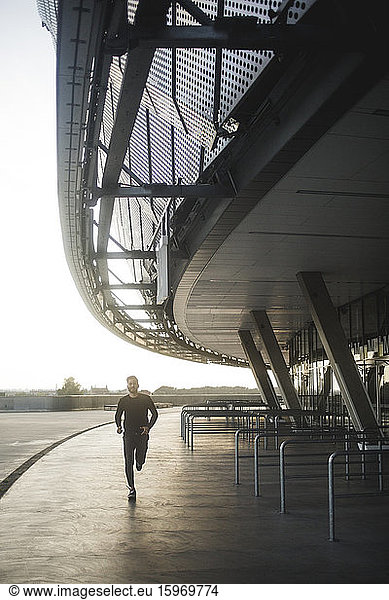 Young man running by built structure against sky