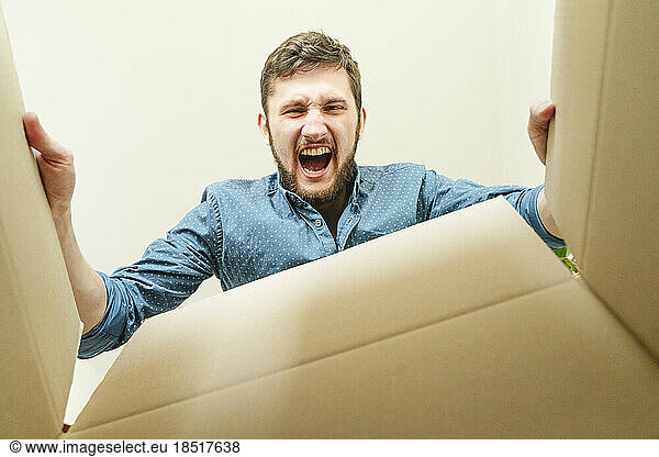 Young man screaming and looking inside cardboard box