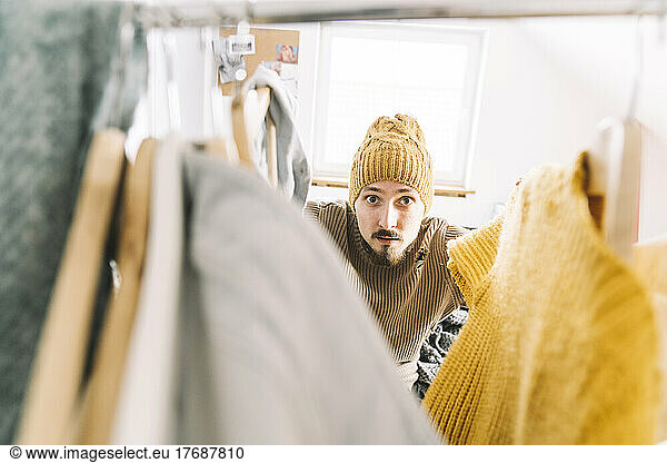 Young man searching for warm clothes in wardrobe