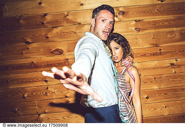 Young man showing stop gesture while embracing woman against wall in party