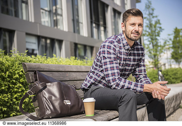 Young man sitting on a bench with coffee