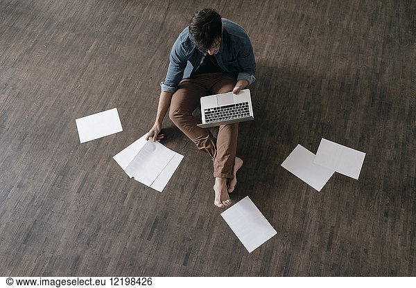 Young man sitting on floor working with laptop