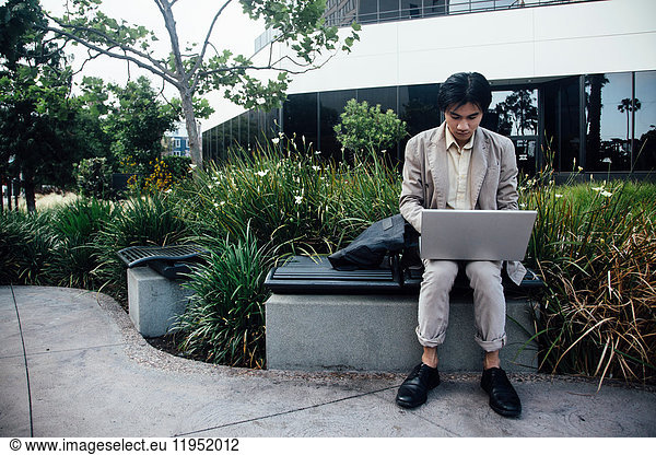 Young man sitting outdoors  using laptop