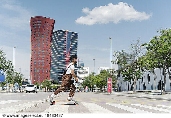 Young man skateboarding on zebra crossing in city