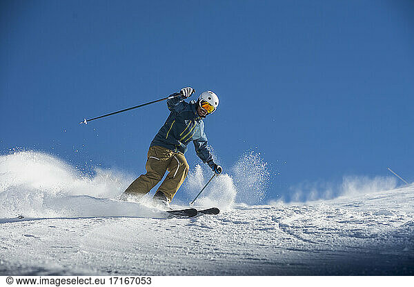 Young man skiing on snow against blue clear sky