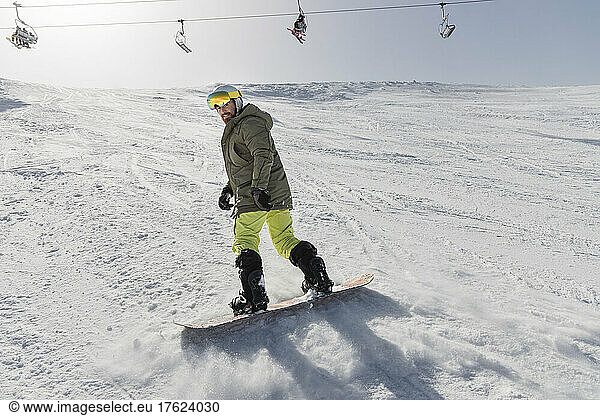 Young man snowboarding on snowcapped mountain