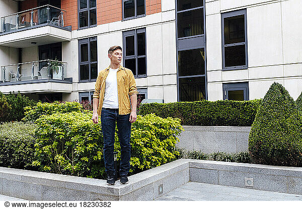 Young man standing on wall in front of building