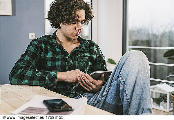 Young man studying through tablet PC at home