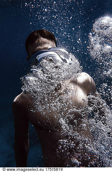 young man swimming between bubbles in the sea of Tenerife