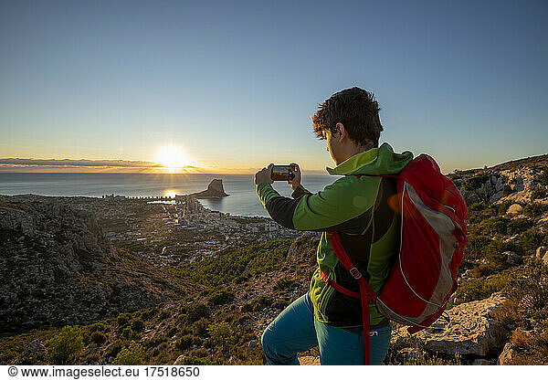 Young man take pictures at sunrise over rocky landscape,  Costa Blanca