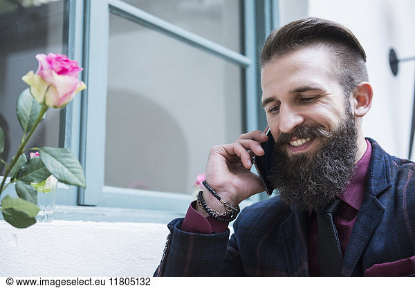 Young man talking on phone at cafe