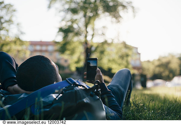 Young man using mobile phone while lying on grass
