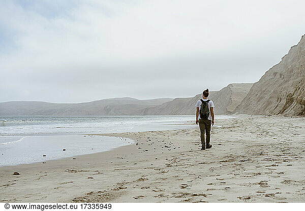 Young man walking on sand at beach in Point Reyes  California  USA