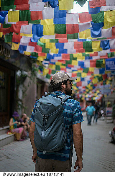 Young man walking streets of Nepal with Himalayan Flags