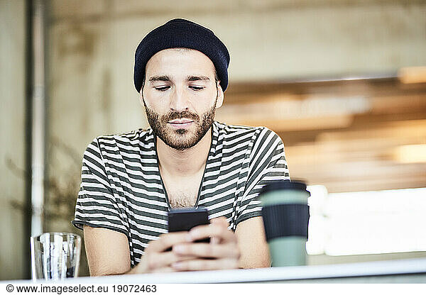 Young man wearing a beanie using cell phone