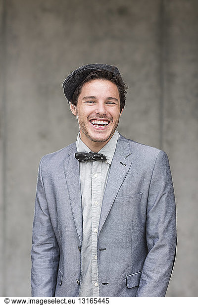 Young man wearing flat cap and bow tie  laughing