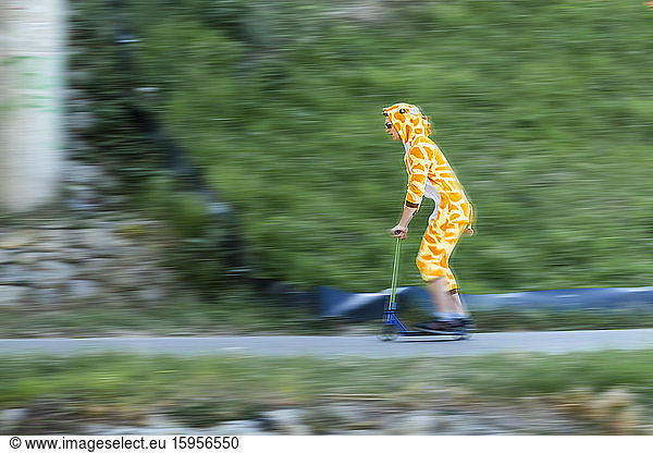 Young man wearing giraffe costume on scooter