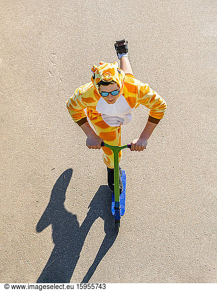 Young man wearing giraffe costume on scooter from above