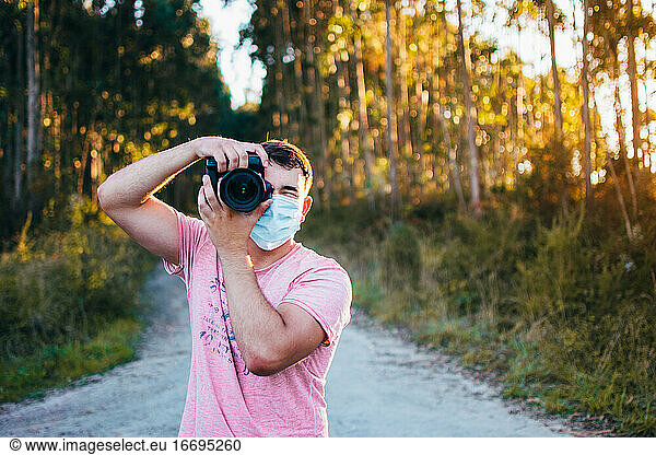 Young man wearing mask and taking a photograph