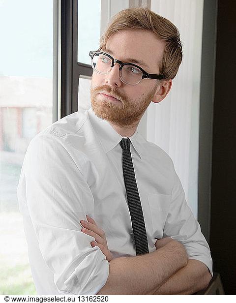 Young man wearing spectacles and tie looking away