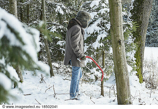 Young man with a saw in forest in winter  Bavaria  Germany