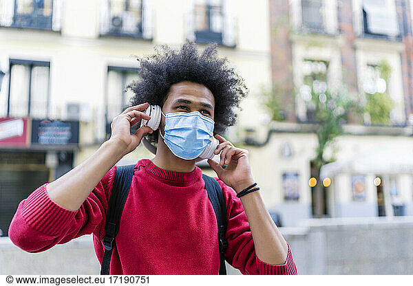 young man with afro hair listening to music from his smartphone