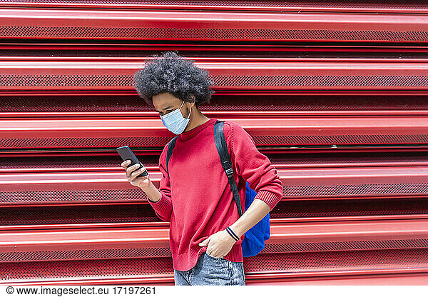 young man with afro hair sending a message from his smartphone