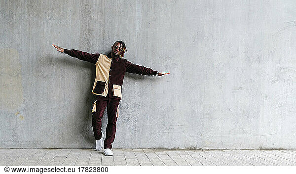 Young man with arms outstretched leaning on concrete wall
