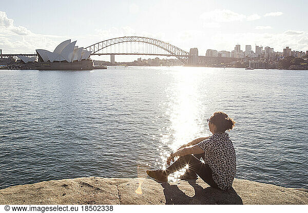 Young man with curly hair  at Sydney harbour  during golden sunset