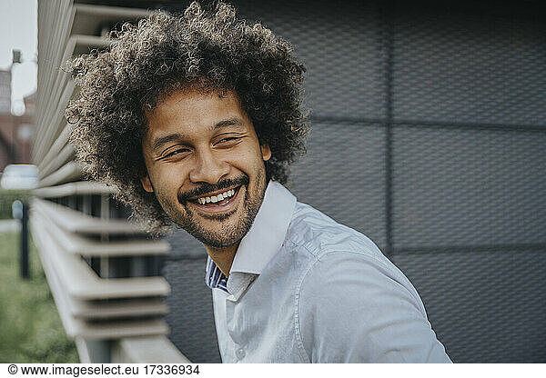 Young man with curly hair looking away while laughing