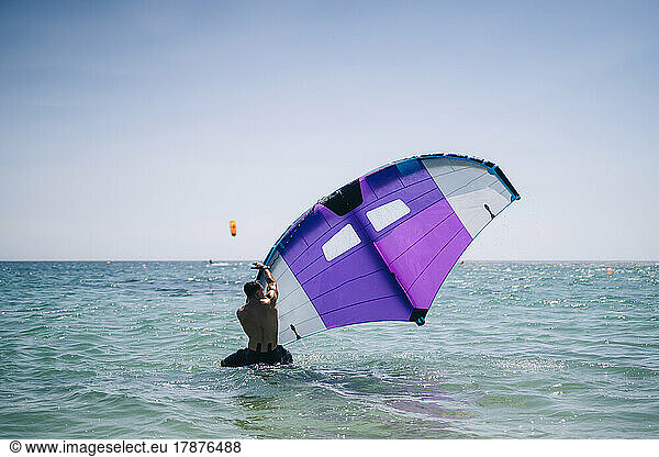 Young man with hydrofoil in sea on sunny day