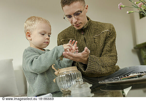 Young man with son counting coins at home