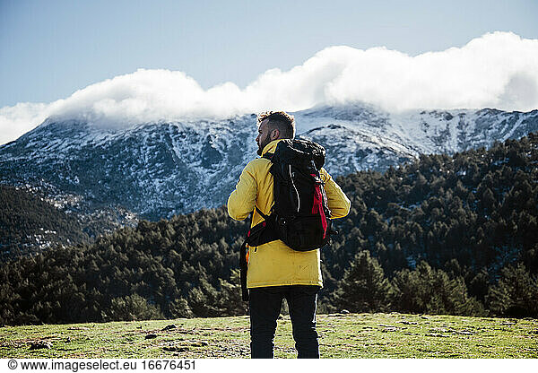 Young man with yellow jacket and backpack in the mountains.