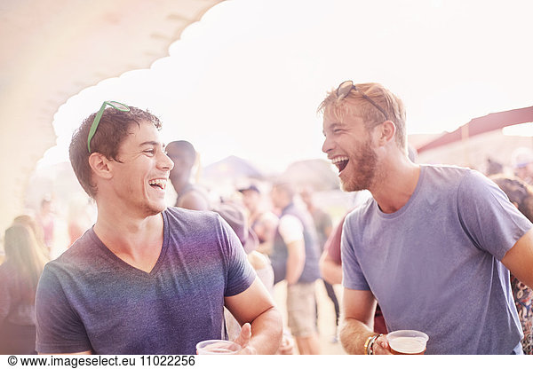 Young men drinking and laughing at music festival