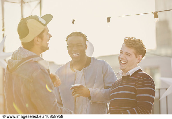 Young men laughing at rooftop party