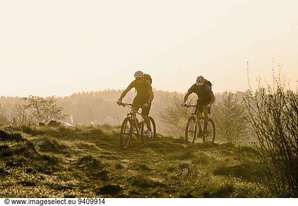 Young men mountainbiking at sunrise