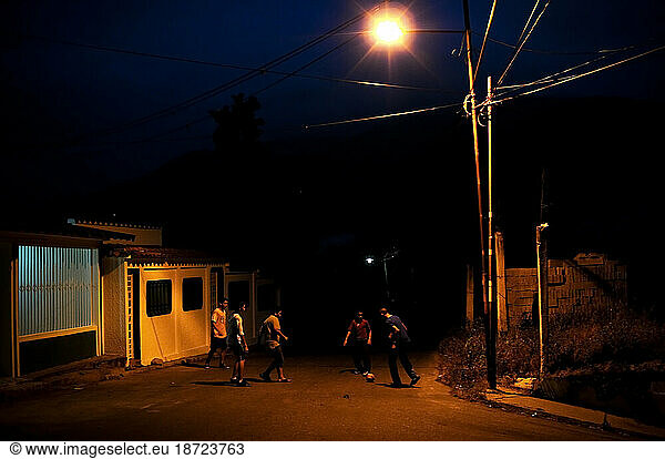 Young men play soccer in the street at night in Tovar  Venezuela.
