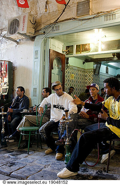 Young men sitting in a cafe at the Medina  smoking water pipes