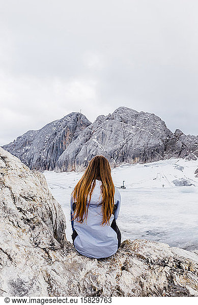 young millennial girl enjoys the views of the Alps standing on glacier