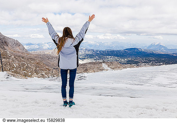 young millennial girl enjoys the views of the Alps standing on glacier